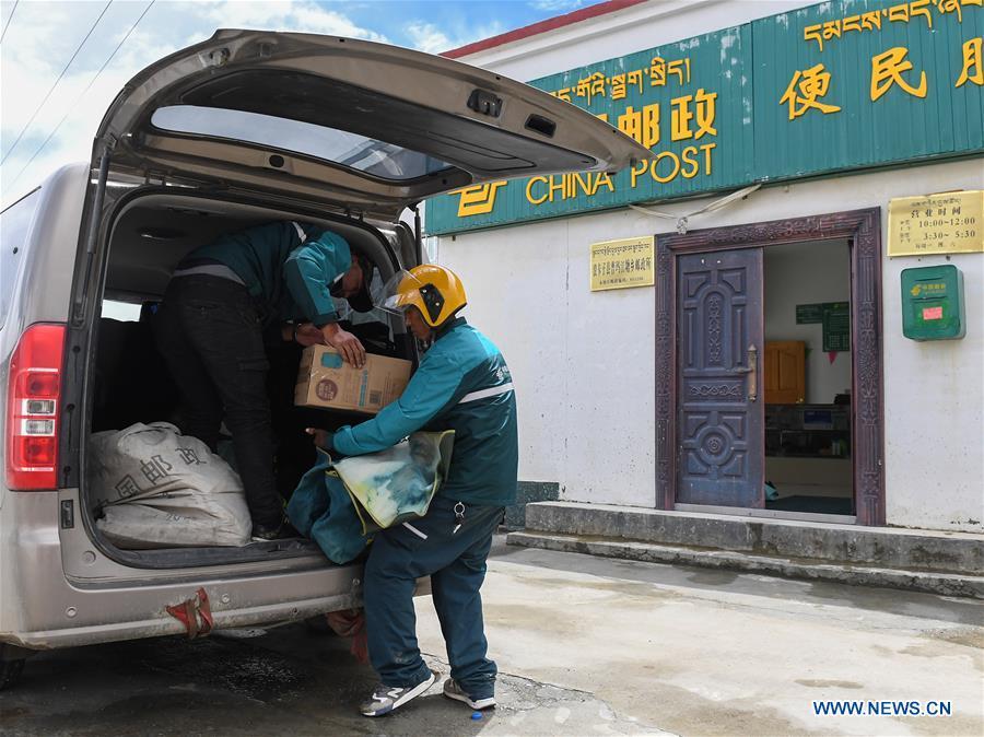 Motorbike courier Gesang Cering (R) and a workmate unload postal packages at the township branch of China Post in Pumaqangtang Township of Nagarze County in Shannan, southwest China\'s Tibet Autonomous Region, July 27, 2018. In Pumaqantang Township, the highest township in China, working as a postal service staff means delivering mails to addresses at altitudes of 5,000 meters and above. Gesang Cering, 29, is a motorbike courier with the local township branch of China Post. Twice a week, Gesang calls on the plateau villages under the township on a 160-km route, coping with extreme oxygen and temperature conditions. Despite its harsh geography, Tibet Autonomous Region has substantially improved the local postal service over the four decades since China\'s reform and opening up. By the end of 2017, the postal road network had managed to cover all towns and counties within the autonomous region. (Xinhua/Li He)
