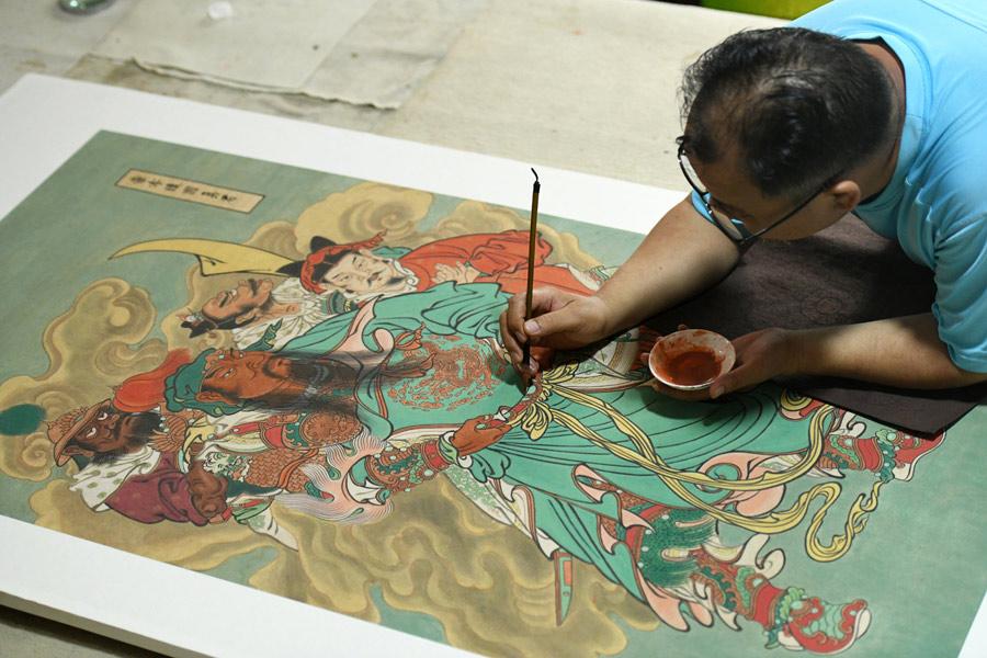 Yao Shulong makes a replica of a traditional Chinese New Year painting of Pilu Temple in his studio on July 24, 2018.  (Photo/Xinhua)