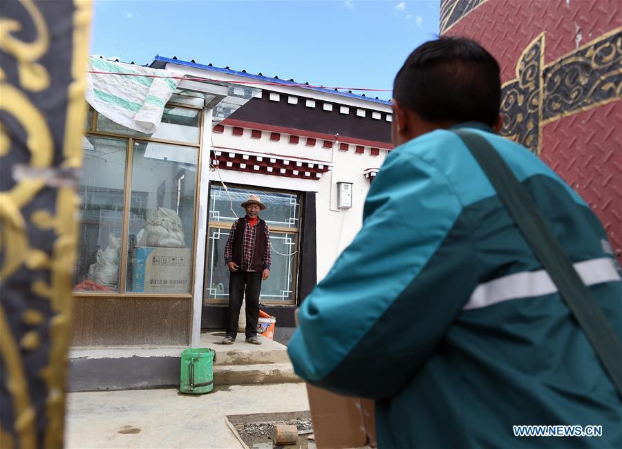 Motorbike courier Gesang Cering delivers a mail package to a client in Pumaqangtang Township of Nagarze County in Shannan, southwest China\'s Tibet Autonomous Region, July 27, 2018. In Pumaqantang Township, the highest township in China, working as a postal service staff means delivering mails to addresses at altitudes of 5,000 meters and above. Gesang Cering, 29, is a motorbike courier with the local township branch of China Post. Twice a week, Gesang calls on the plateau villages under the township on a 160-km route, coping with extreme oxygen and temperature conditions. Despite its harsh geography, Tibet Autonomous Region has substantially improved the local postal service over the four decades since China\'s reform and opening up. By the end of 2017, the postal road network had managed to cover all towns and counties within the autonomous region. (Xinhua/Li He)