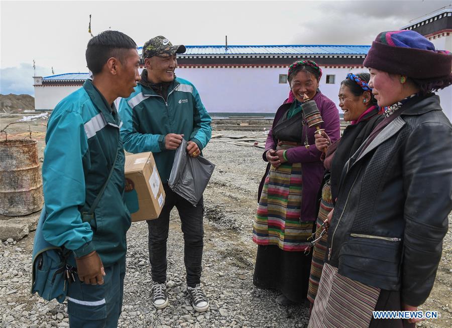 Motorbike courier Gesang Cering (1st L) and his workmate Cering Quba (2nd L) talk with clients in Pumaqangtang Township of Nagarze County in Shannan, southwest China\'s Tibet Autonomous Region, July 27, 2018. In Pumaqantang Township, the highest township in China, working as a postal service staff means delivering mails to addresses at altitudes of 5,000 meters and above. Gesang Cering, 29, is a motorbike courier with the local township branch of China Post. Twice a week, Gesang calls on the plateau villages under the township on a 160-km route, coping with extreme oxygen and temperature conditions. Despite its harsh geography, Tibet Autonomous Region has substantially improved the local postal service over the four decades since China\'s reform and opening up. By the end of 2017, the postal road network had managed to cover all towns and counties within the autonomous region. (Xinhua/Li He)