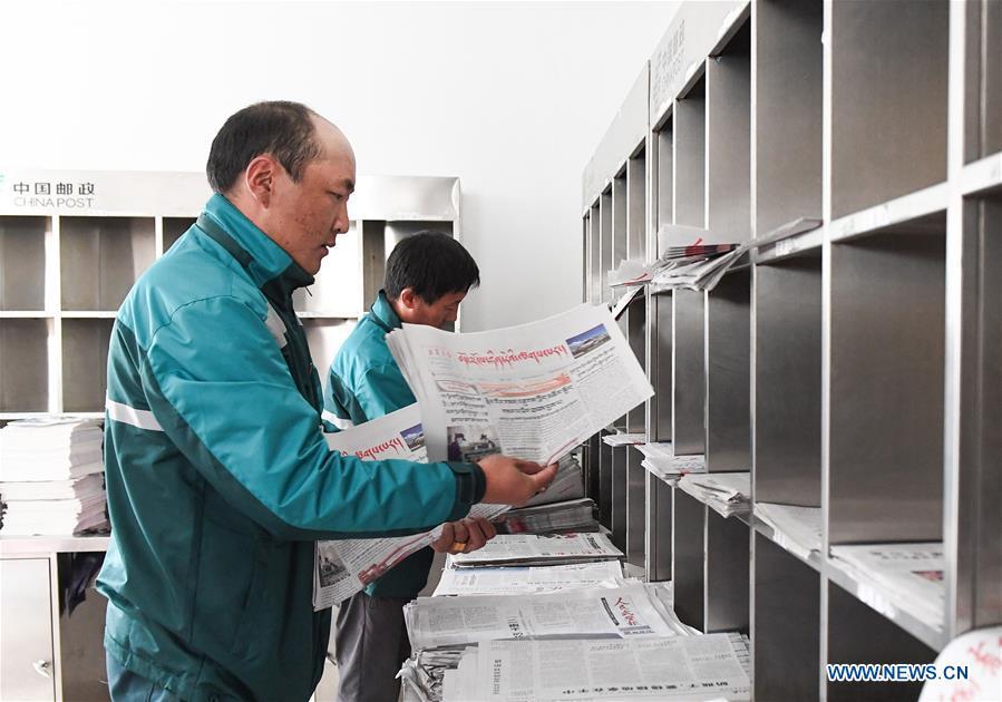 Postal courier Cering Quba sorts newspapers at the county branch of China Post in Nagarze County in Shannan, southwest China\'s Tibet Autonomous Region, July 23, 2018. In Pumaqantang Township, the highest township in China, working as a postal service staff means delivering mails to addresses at altitudes of 5,000 meters and above. Gesang Cering, 29, is a motorbike courier with the local township branch of China Post. Twice a week, Gesang calls on the plateau villages under the township on a 160-km route, coping with extreme oxygen and temperature conditions. Despite its harsh geography, Tibet Autonomous Region has substantially improved the local postal service over the four decades since China\'s reform and opening up. By the end of 2017, the postal road network had managed to cover all towns and counties within the autonomous region. (Xinhua/Li He)