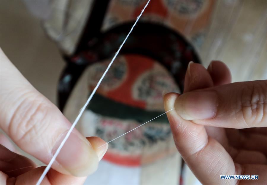 A worker processes thread in east China\'s Jiangsu Province, July 25, 2018. An exhibition displaying Wang Qin\'s collections and creations of Suzhou embroidery version of classic Chinese painting works concluded in Suzhou on Sunday. (Xinhua/Yang Lei)