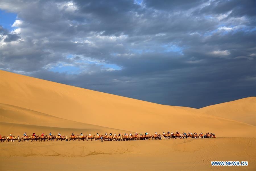 Tourists ride camels at the Mingsha Mountain and Crescent Spring scenic spot in Dunhuang, northwest China\'s Gansu Province, July 29, 2018. (Xinhua/Zhang Xiaoliang)