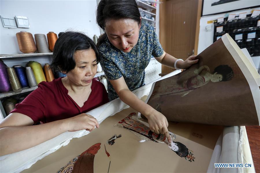 Wang Qin (R) and embroidery worker Lu Xuezhen compare embroidery and painting works in east China\'s Jiangsu Province, July 25, 2018. An exhibition displaying Wang Qin\'s collections and creations of Suzhou embroidery version of classic Chinese painting works concluded in Suzhou on Sunday. (Xinhua/Yang Lei)