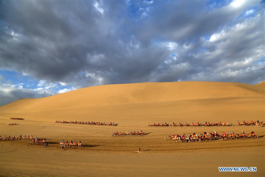 Tourists ride camels at the Mingsha Mountain and Crescent Spring scenic spot in Dunhuang, northwest China\'s Gansu Province, July 29, 2018. (Xinhua/Zhang Xiaoliang)