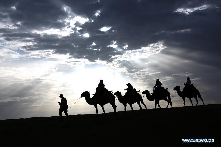 Tourists ride camels at the Mingsha Mountain and Crescent Spring scenic spot in Dunhuang, northwest China\'s Gansu Province, July 29, 2018. (Xinhua/Zhang Xiaoliang)