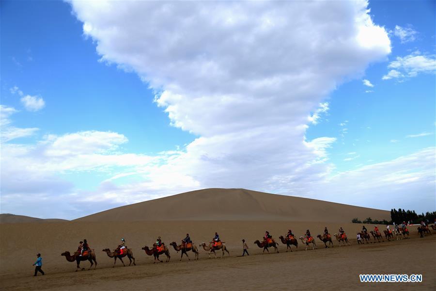 Tourists ride camels at the Mingsha Mountain and Crescent Spring scenic spot in Dunhuang, northwest China\'s Gansu Province, July 29, 2018. (Xinhua/Zhang Xiaoliang)