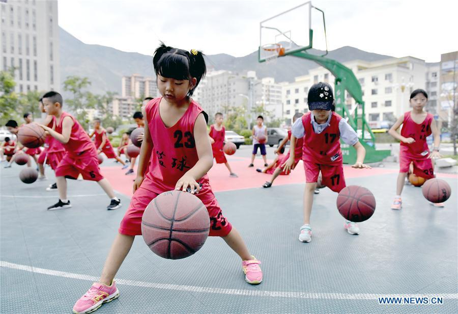 Children practice basketball in front of a gym in Longnan City, northwest China\'s Gansu Province, July 28, 2018. Children take part in various classes and activities to enrich their summer vacation life. (Xinhua/Ran Chuangchang)