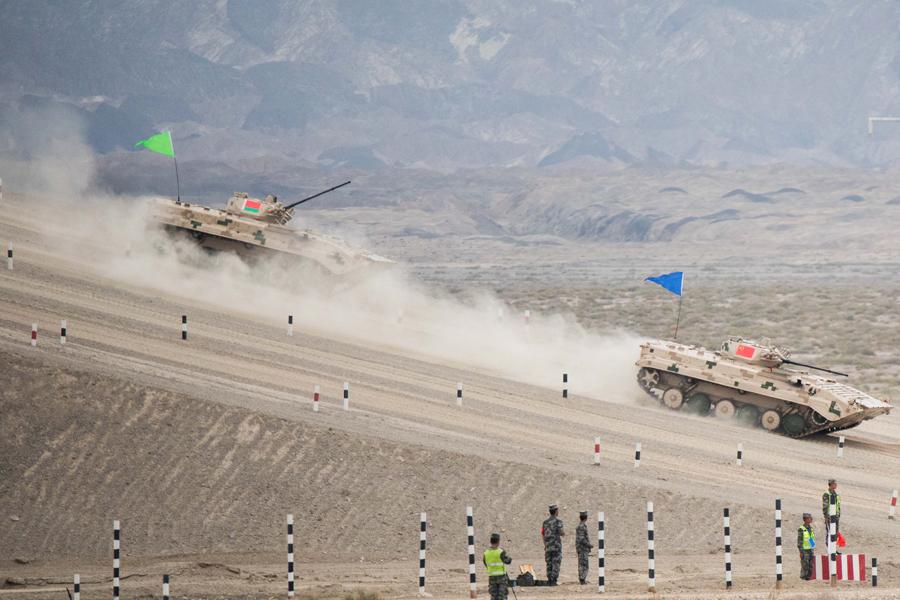 An infantry fighting vehicle (right) of the People\'s Liberation Army participates in the Suvorov Attack race during the International Army Games 2018 in Korla, Xinjiang Uygur autonomous region on Monday. XU KANGPING/FOR CHINA DAILY  

The International Army Games 2018 began on Sunday with four contests in the Xinjiang Uygur autonomous region and Fujian province.

Seventeen teams comprising 358 soldiers from 11 countries are participating in the contests, which will conclude on Aug 11. Some other countries sent observers to the events.

Three of the contests－the Suvorov Attack race and shooting competition by infantry fighting vehicles; the Clear Sky test for air-defense missile units; and the Safe Route contest, which requires teams to make their way through a minefield and other obstacles－take place in Korla, Xinjiang.

In coastal Quanzhou, Fujian, a seaborne assault contest is being organized by the People\'s Liberation Army Navy, marking the first time the Chinese Navy has hosted a contest in the Games. Marines from Iran, Russia, Sudan, Venezuela and China will compete in this event, which consists of an obstacle course, survival trail and relay race.

The Games, initiated by the Russian Ministry of Defense in 2014, currently cover more than 20 professional areas for armies, navies and air forces.

With the participation of about 30 countries, the international influence of the games has increased each year.

Many countries and their armed forces want to project strength through the platform, said Kong Jun, head of the Seaborne Assault organization committee and commander of the PLA Navy Marine Corps.

\