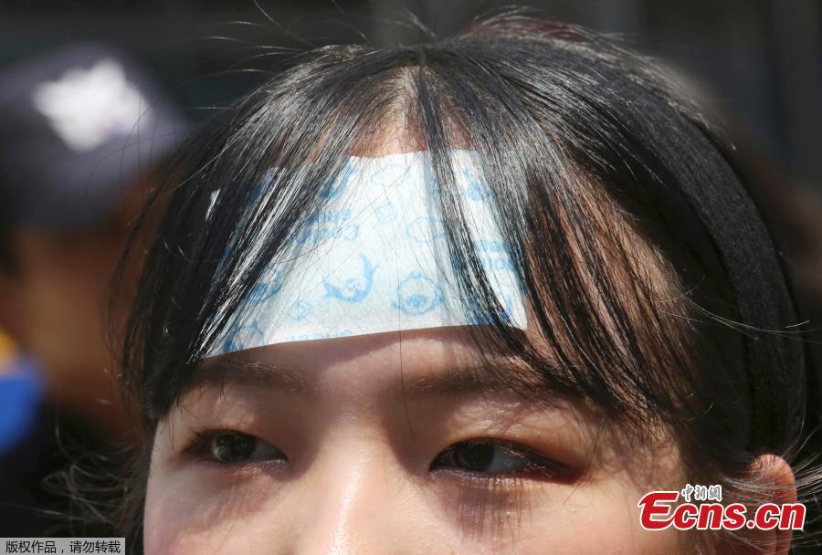 A middle school student attaches a cooling sheet on her forehead amid the sweltering heat during a rally demanding full compensation and apology for wartime sex slaves from Japanese government in front of the Japanese embassy in Seoul, South Korea, Aug. 1, 2018. South Korean Meteorological Administration issued a heat wave warning for Seoul and other cities. (Photo/Agencies)