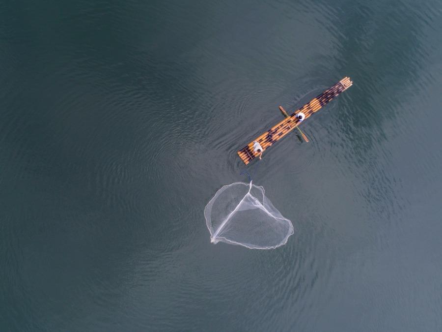 Fishermen cast nets on a bamboo raft on Qiandao Lake, Hangzhou city, Zhejiang Province, Aug. 2, 2018. After a three-month break, fishermen resume a new round of catches in the area, where rural tourism and recreational fishing are highlights of the local industry. [Photo/Xinhua]