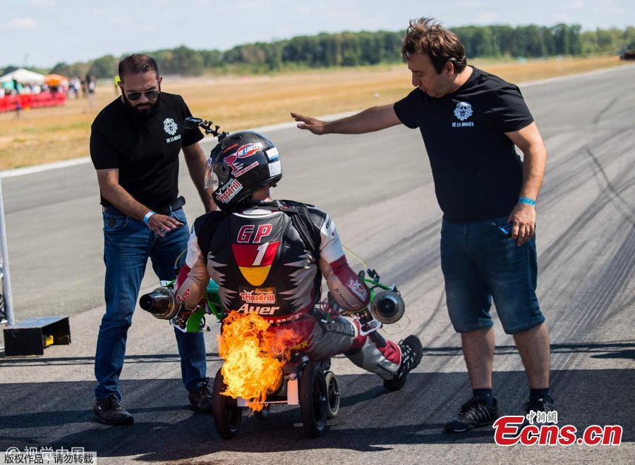 German extreme athlete Dirk Auer sits on his Bobby car while flames burst out under the engine during an airport racing event in Bottrop-Kirchhellen, western Germany, Aug. 5, 2018. (Photo/Agencies)