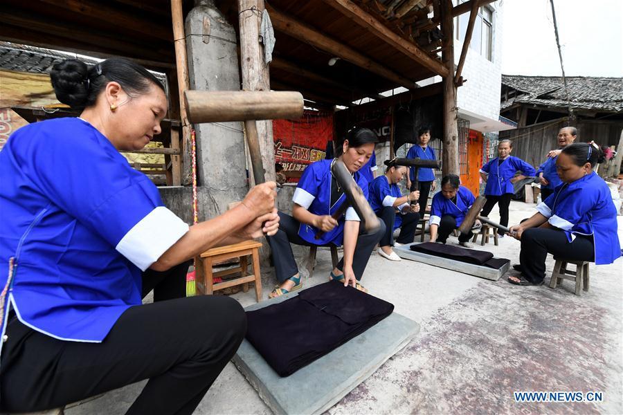 Women of the Dong ethnic group beat Dong cloth at Linxi Village of Sanjiang Dong Autonomous County under Liuzhou City, south China\'s Guangxi Zhuang Autonomous Region, Aug. 4, 2018. Summer is the best season for the people of the Dong ethnic group to make their traditional Dong cloth in ancient ways with natural materials. It is popular among the Dong people for its shining look in the sun and cozy quality for wearing. (Xinhua/Li Hanchi)