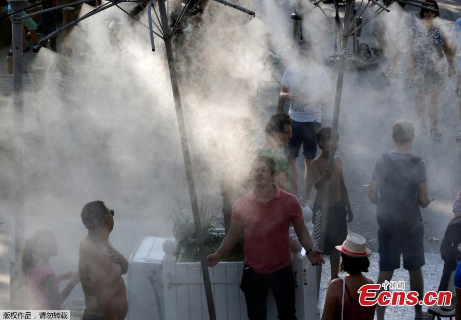 People stand in a spray water to cool off as a summer heatwave with high temperatures continues in Paris, France, August 4, 2018. Europe’s heatwave gripped Spain and Portugal on Friday, as governments checked for forest fires, a Budapest game reserve fed its animals iced snacks and a Finnish supermarket invited customers to sleep over to stay cool. (Photo/Agencies)