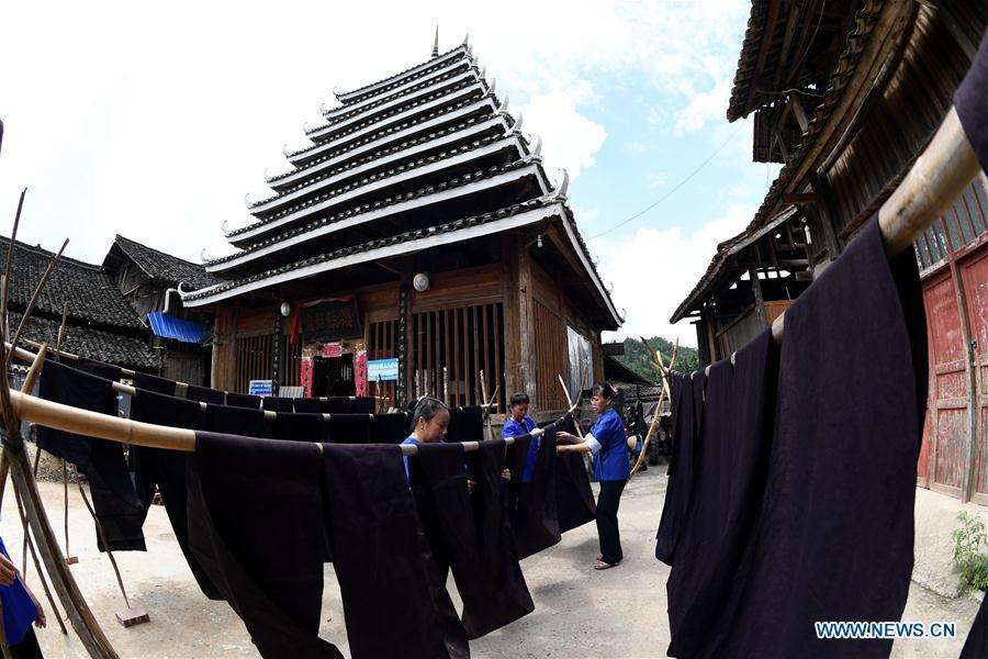 Women of the Dong ethnic group dry Dong cloth at Linxi Village of Sanjiang Dong Autonomous County under Liuzhou City, south China\'s Guangxi Zhuang Autonomous Region, Aug. 4, 2018. Summer is the best season for the people of the Dong ethnic group to make their traditional Dong cloth in ancient ways with natural materials. It is popular among the Dong people for its shining look in the sun and cozy quality for wearing. (Xinhua/Li Hanchi)