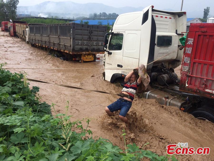 Rescuers help a driver escape from a truck trapped by mountain torrents in Fudian Town, Yanshi City, Central China’s Henan Province, Aug. 5, 2018. Fifteen drivers were saved after a flash flood caused by a two-hour rainstorm trapped 50 trucks. (Photo/VCG)