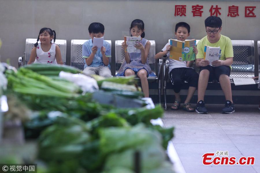 Teenagers learn English from a retiree in an agricultural products market in Hangzhou City, East China’s Zhejiang Province. Mr. Jin, 64, previously worked in a desk job with a public security bureau. The gray-haired man said he learned English when he was young from a radio program. For the past five years, during the school summer holidays, Jin has offered free English tutoring to children in the market. (Photo/VCG)