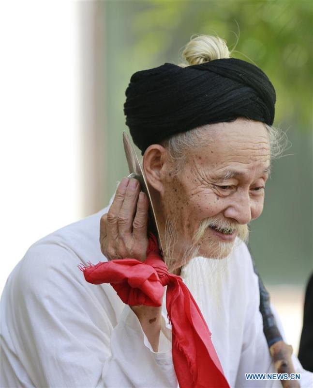 Jin De\'an checks the instrument before performing Daliuzi at Xibu Street, a scenic spot in the Wulingyuan District of Zhangjiajie City, central China\'s Hunan Province, Aug. 7, 2018. Daliuzi is a kind of local musical instrument performance with a long history. Jin De\'an is the creator of \