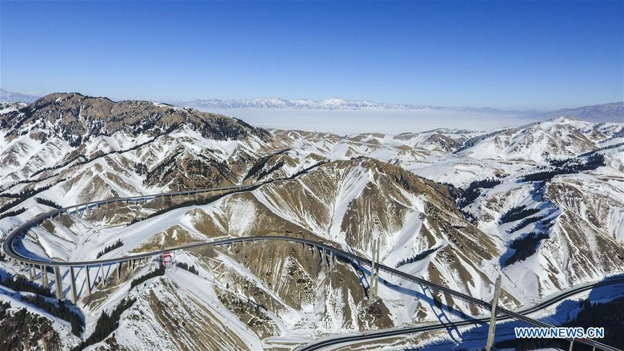 Aerial photo taken on Jan. 26, 2018 shows the Lianyungang-Horgos expressway along the Tianshan Mountains, northwest China\'s Xinjiang Uygur Autonomous Region. As an important link of the Silk Road Economic Belt, Xinjiang is speeding up the development of transportation and logistics to connect east and west. By the end of 2017, the total length of roads in Xinjiang reached 186,000 km, with 4,578 km of expressways. (Xinhua/Hu Huhu)