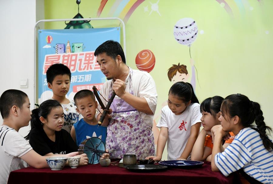 Li Junhang teaches local students the craftsmanship of porcelain restoration in Shijiazhuang, Hebei Province, Aug. 8, 2018.  (Photo/Xinhua)