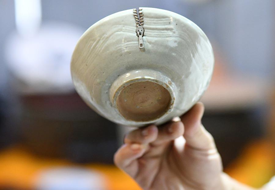 A broken porcelain ware is restored with an artistic touch, resembling the look of a zip. (Photo/Xinhua)