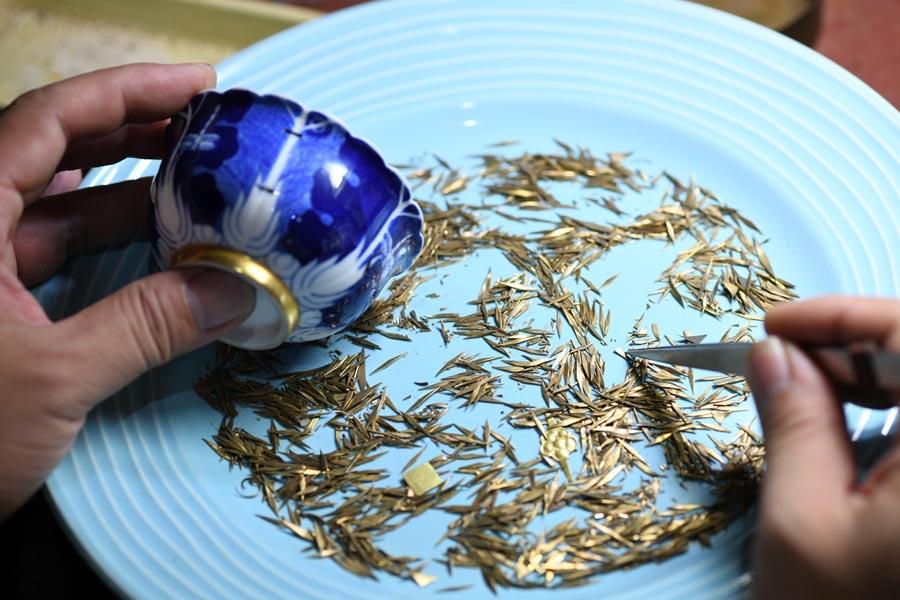 Li Junhang picks a suitable nail for a broken porcelain bowl, at his studio in North China\'s Hebei Province, Aug. 6, 2018.  (Photo/Xinhua)