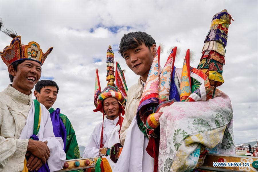 A herdsman(R) introduces his costume before the opening ceremony of a horse racing festival in Damxung County, southwest China\'s Tibet Autonomous Region, Aug. 8, 2018. Dangjiren horse racing is originated from military parade of Mongolian cavalry since 17th century. (Xinhua/Cen Yunpeng)