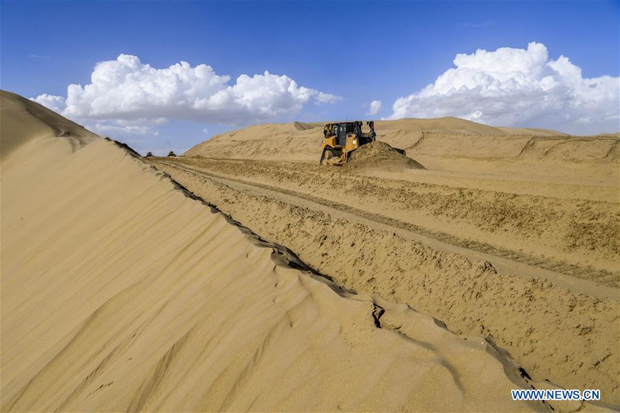 Photo taken on July 5, 2018 shows the construction site of the desert road linking Yuli County to Qiemo County in northwest China\'s Xinjiang Uygur Autonomous Region. As an important link of the Silk Road Economic Belt, Xinjiang is speeding up the development of transportation and logistics to connect east and west. By the end of 2017, the total length of roads in Xinjiang reached 186,000 km, with 4,578 km of expressways. (Xinhua/Hu Huhu)
