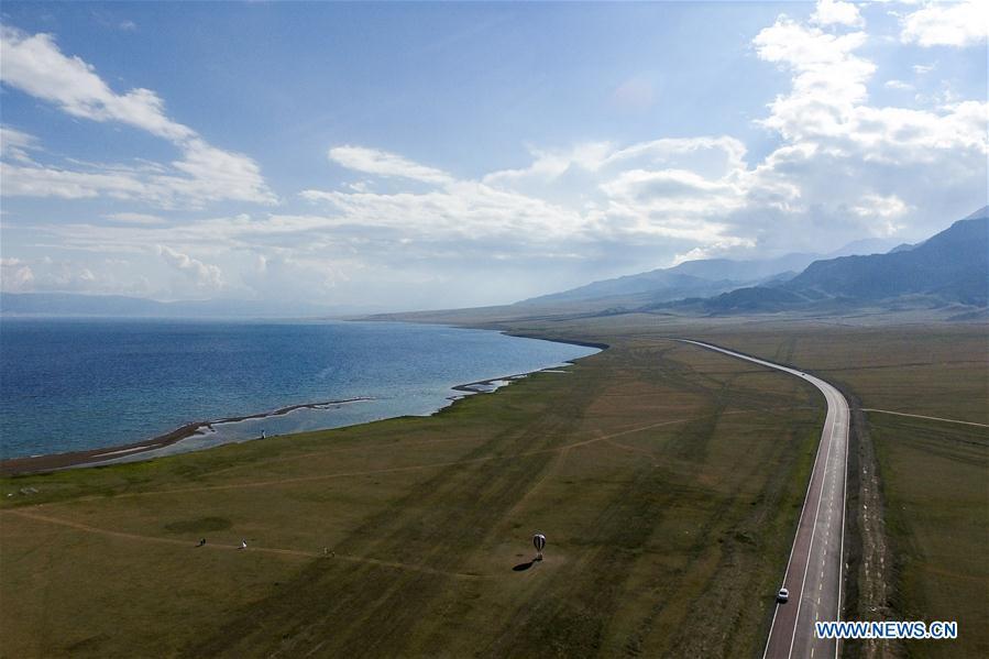 Aerial photo taken on July 5, 2018 shows the Lianyungang-Horgos expressway along the Sayram Lake, northwest China\'s Xinjiang Uygur Autonomous Region. As an important link of the Silk Road Economic Belt, Xinjiang is speeding up the development of transportation and logistics to connect east and west. By the end of 2017, the total length of roads in Xinjiang reached 186,000 km, with 4,578 km of expressways. (Xinhua/Zhao Ge)