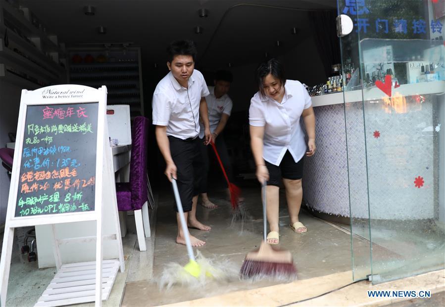 Staff of a shop drain the floodwater in Haikou, south China\'s Hainan Province, Aug. 10, 2018. Hainan was hit by heavy rainfalls under the influence of a tropical depression on Friday, which triggered a red alert for rainstorms in seven cities and counties, including Haikou. (Xinhua/Wang Junfeng)