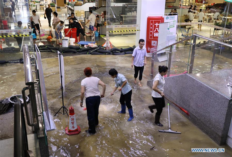Staff of a shop drain the floodwater in Haikou, south China\'s Hainan Province, Aug. 10, 2018. Hainan was hit by heavy rainfalls under the influence of a tropical depression on Friday, which triggered a red alert for rainstorms in seven cities and counties, including Haikou. (Xinhua/Wang Junfeng)