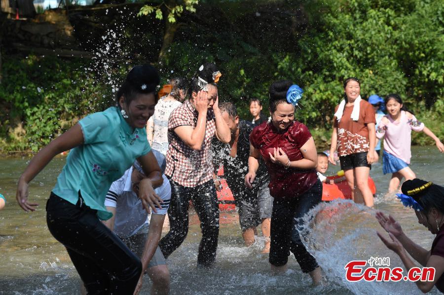 People from the Miao ethnic group catch fish barehanded or with tools during a folk festival at a river in Taijiang County, Southwest China\'s Guizhou Province, Aug. 12, 2018. The fishing festival, held on July 2 of the lunar calendar, which falls on Aug. 12 this year, is a chance for recreation and bonding among locals. (Photo: China News Service/Liu Kaifu)