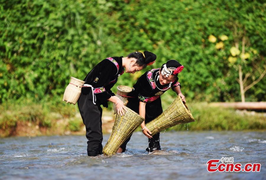 People from the Miao ethnic group catch fish barehanded or with tools during a folk festival at a river in Taijiang County, Southwest China\'s Guizhou Province, Aug. 12, 2018. The fishing festival, held on July 2 of the lunar calendar, which falls on Aug. 12 this year, is a chance for recreation and bonding among locals. (Photo: China News Service/Liu Kaifu)