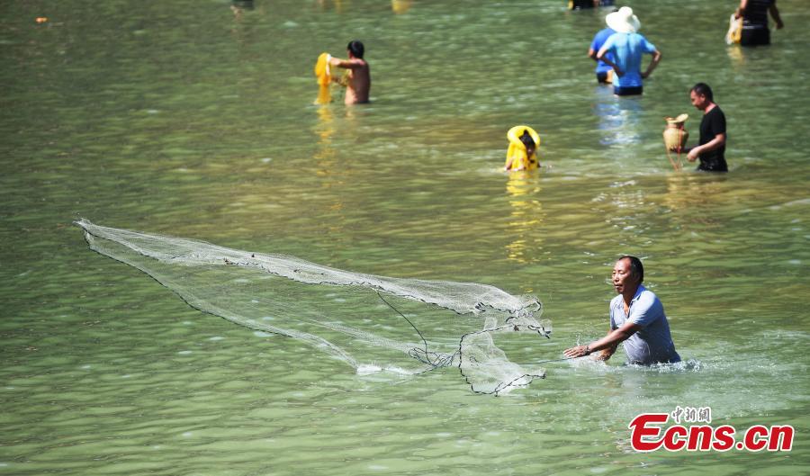 People from the Miao ethnic group catch fish barehanded or with tools during a folk festival at a river in Taijiang County, Southwest China\'s Guizhou Province, Aug. 12, 2018. The fishing festival, held on July 2 of the lunar calendar, which falls on Aug. 12 this year, is a chance for recreation and bonding among locals. (Photo: China News Service/Liu Kaifu)