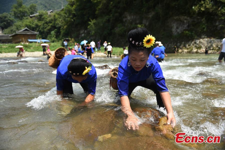 People from the Miao ethnic group catch fish barehanded or with tools during a folk festival at a river in Taijiang County, Southwest China\'s Guizhou Province, Aug. 12, 2018. The fishing festival, held on July 2 of the lunar calendar, which falls on Aug. 12 this year, is a chance for recreation and bonding among locals. (Photo: China News Service/Liu Kaifu)