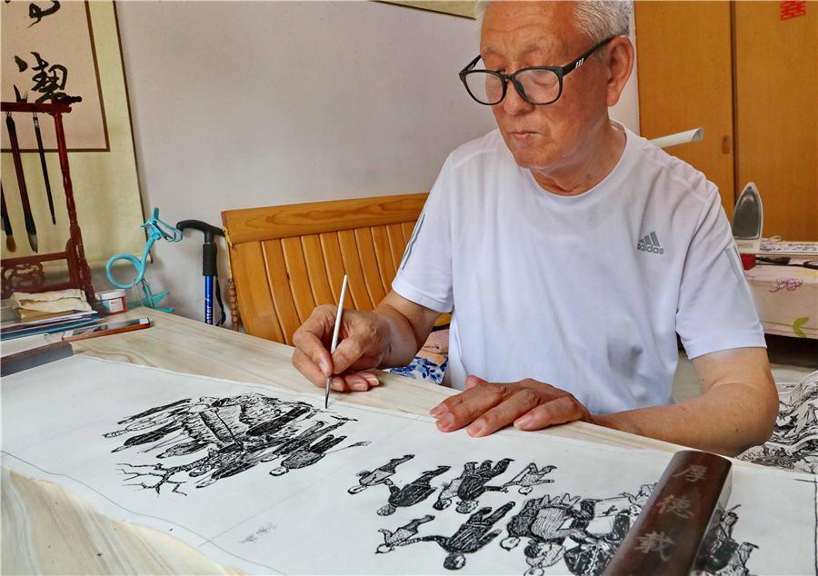 Wang Jingtang showcases his painting at his home in Qinhuangdao, North China\'s Hebei Province, on Aug. 10, 2018.