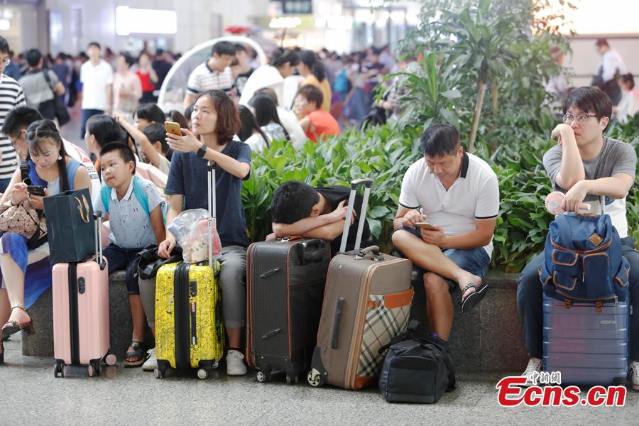 Passengers wait to change or refund tickets at a railway station in Shanghai, Aug. 13, 2018, after several trains were canceled due to Typhoon Yagi. Emergency rescuers are bracing for this year\'s 14th typhoon in the metropolis. (Photo: China News Service/Yin Liqin)