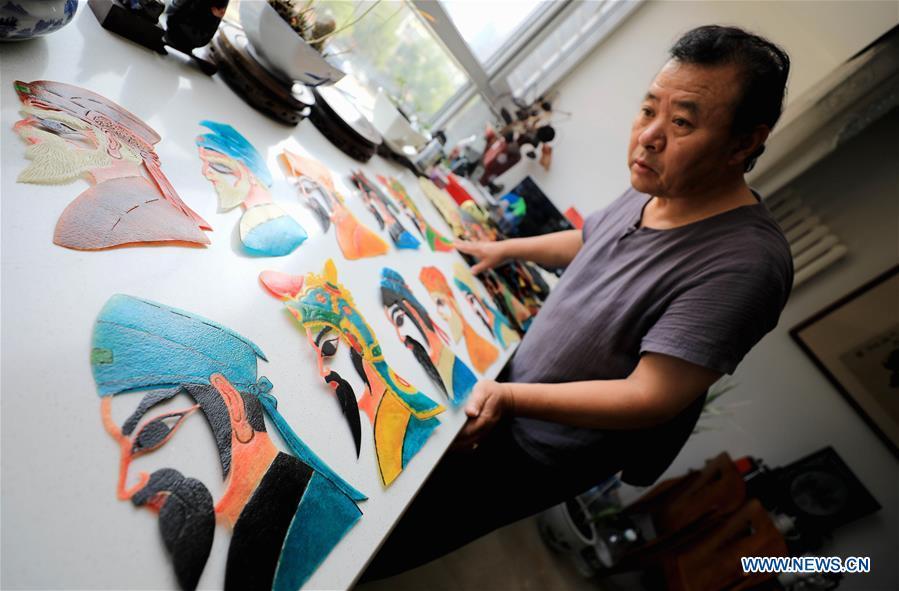 Li Wei shows shadow puppets made by himself in Jinan, east China\'s Shandong Province, July 5, 2018. Li, 63, is the son of Jinan shadow puppet show master Li Xingtang. He learned shadow puppet performance from his father in childhood. After his father passed away 11 years ago, Li Wei took over the task of developing and innovating the art of Jinan puppet show. Since last summer, Li has kept on presenting traditional shadow puppet plays at the Baihuazhou scenic area in Jinan every weekend for free. (Xinhua/Zhao Xiaoming)
