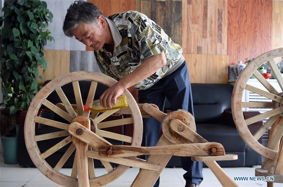 He Yong lubricates the bearing of a wooden bicycle in Liuhu Township of Pingliang City, northwest China\'s Gansu Province, Aug. 14, 2018. The 55-year-old farmer He Yong successfully made a 1.8-meter-long and 0.98-meter-high wooden bicycle in 2017. The bike was made purely of wood, including walnut and elm. (Xinhua/Fan Peishen)