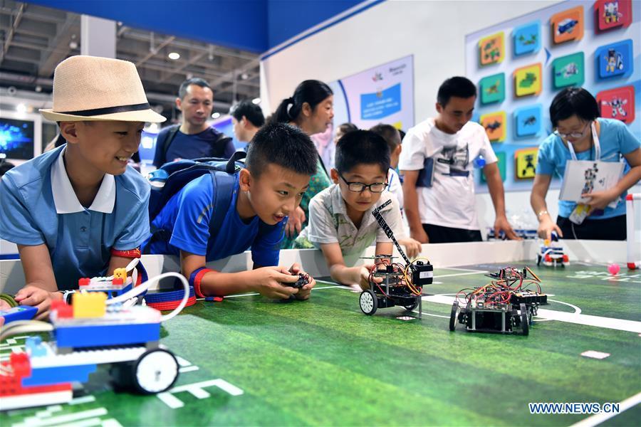 Children look at programming robots at World Robot Conference 2018 in Beijing, capital of China, Aug. 15, 2018. Kicking off on Wednesday, the conference attracted more than 160 domestic and international corporations exhibiting their cutting-edge products in the robotics industry. (Xinhua/Li Xin)