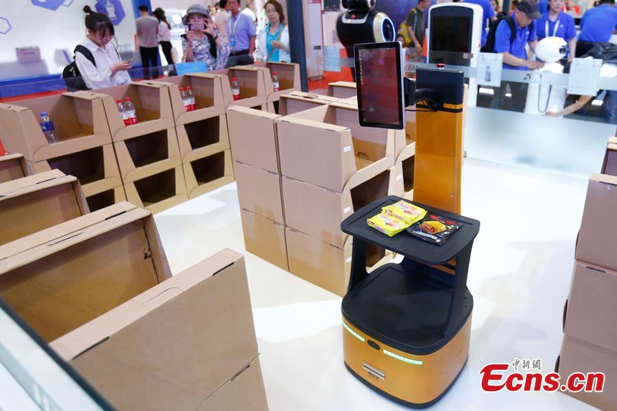 Visitors look at robots on display at the World Robot Conference 2018 in Beijing, Aug. 15, 2018. The conference included a competitive section, which attracted contestants from 16 countries and regions. (Photo: China News Service/Fu Tian)