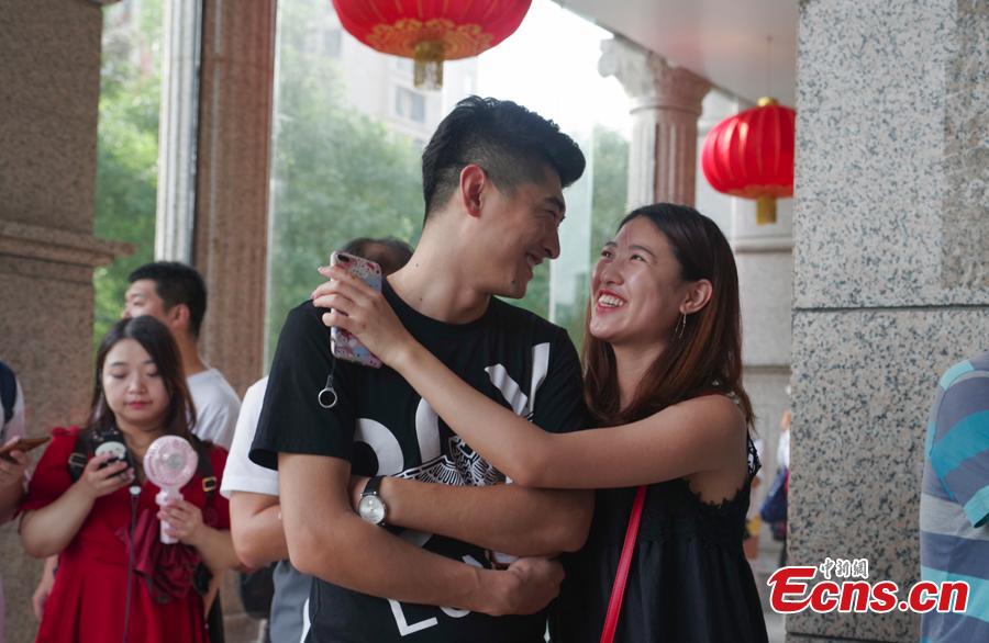A couple poses for a photo as they complete their marriage registration at the civil affairs department in Taiyuan City, Shanxi Province, Aug. 17, 2018 on the Qixi Festival, known as China’s Valentine\'s Day. Falling on the seventh day of the seventh lunar month on the Chinese calendar, the festival celebrates the annual meeting of a cowherd and weaver girl in Chinese mythology. Some reportedly got up at 5 am to register on a day considered auspicious. (Photo: China News Service/Wu Junjie)