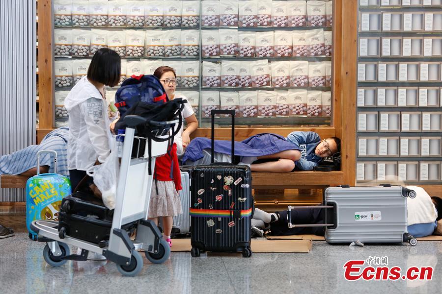 Passengers wait at the departure hall of Pudong International Airport in Shanghai, Aug. 17, 2018. Some flights in Hongqiao International Airport and Putong International Airport in Shanghai were delayed or cancelled due to the Typhoon Rumbia. （Photo: China News Service/Yin Liqin）