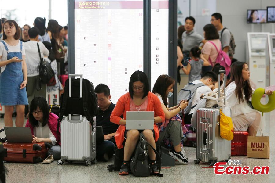 Passengers wait at the departure hall of Pudong International Airport in Shanghai, Aug. 17, 2018. Some flights in Hongqiao International Airport and Putong International Airport in Shanghai were delayed or cancelled due to the Typhoon Rumbia. （Photo: China News Service/Yin Liqin）