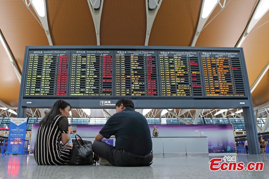 Passengers wait at the departure hall of Pudong International Airport in Shanghai, Aug. 17, 2018. Some flights in Hongqiao International Airport and Putong International Airport in Shanghai were delayed or cancelled due to the Typhoon Rumbia. （Photo: China News Service/Yin Liqin）