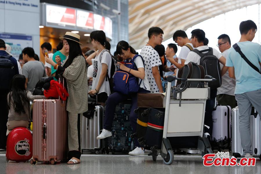 Passengers wait at the departure hall of Pudong International Airport in Shanghai, Aug. 17, 2018. Some flights in Hongqiao International Airport and Putong International Airport in Shanghai were delayed or cancelled due to the Typhoon Rumbia. （Photo: China News Service/Yin Liqin）