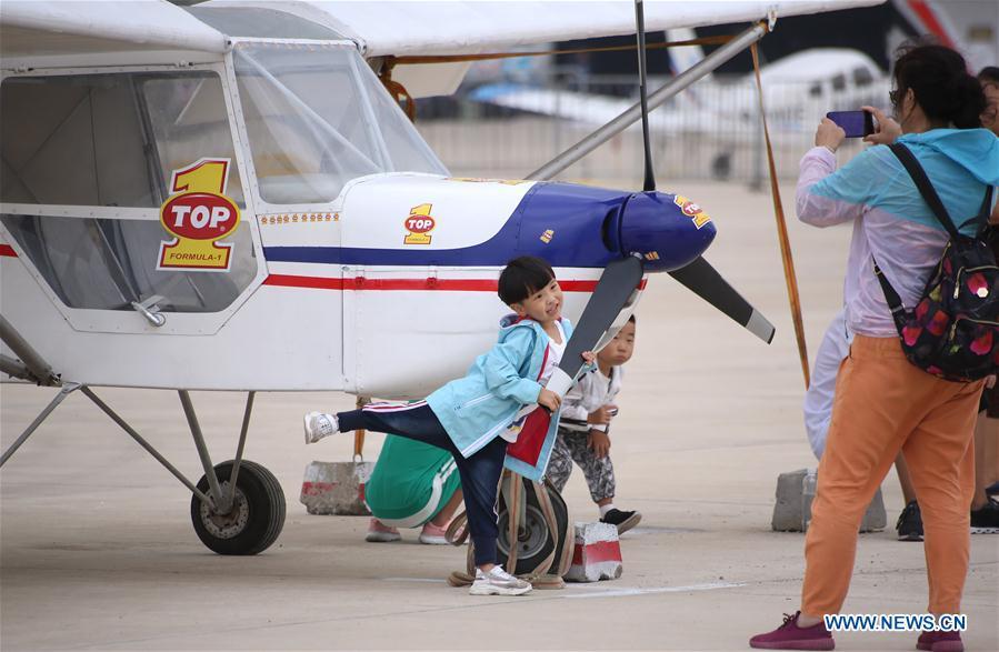 A child poses for photo with a displayed aircraft during the 7th Faku Flight Conference in Shenyang, capital of northeast China\'s Liaoning Province, Aug. 18, 2018. The flight conference kicked off here on Saturday. (Xinhua/Yao Jianfeng)