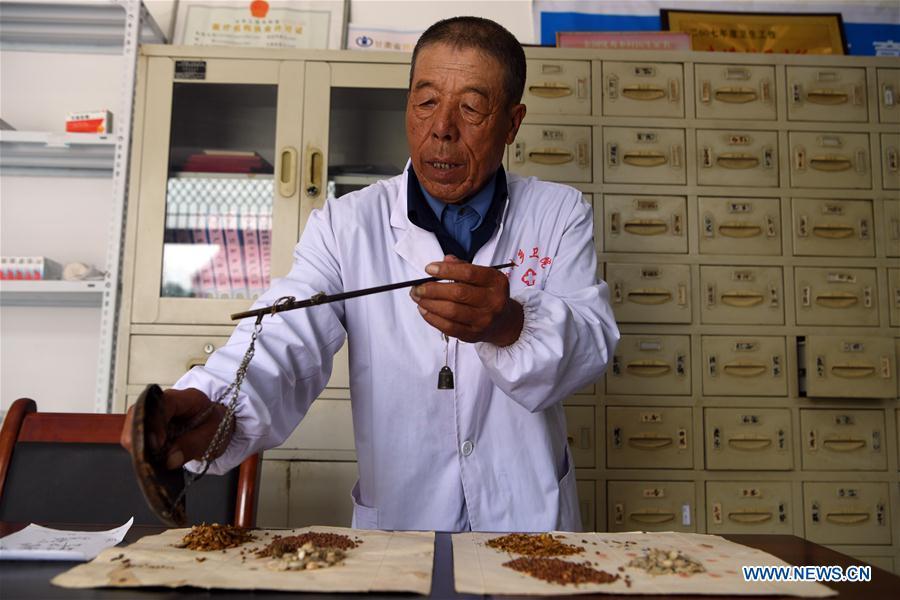 Doctor Wang Guilin dispenses herbs according to a traditional Chinese medicine prescription in Yueming Village of Mawu County in Pingliang, northwest China\'s Gansu Province, Aug. 15, 2018. Wang has been working here as a village-based doctor since 1968. A large number of medical practitioners are active in China\'s rural areas where health care is still underdeveloped. Under adverse working conditions, they have carried forward the humanitarian spirit and devoted themselves to the health of rural citizens. China will mark its first Medical Workers\' Day on Aug. 19, 2018. (Xinhua/Fan Peishen)