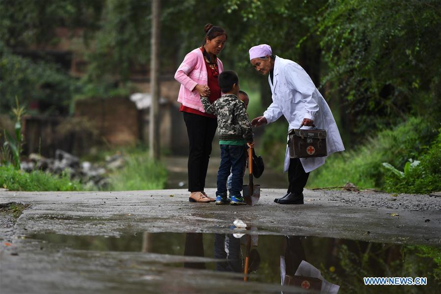 Doctor He Shiying (1st R) asks a sick boy about his health in Meipo Village of Dahejia Township in the Baoan-Dongxiang-Salar Autonomous County of Jishishan, northwest China\'s Gansu Province, Aug. 15, 2018. He Shiying has been working here as a village-based doctor since 1966, when she was 20. A large number of medical practitioners are active in China\'s rural areas where health care is still underdeveloped. Under adverse working conditions, they have carried forward the humanitarian spirit and devoted themselves to the health of rural citizens. China will mark its first Medical Workers\' Day on Aug. 19, 2018. (Xinhua/Chen Bin)