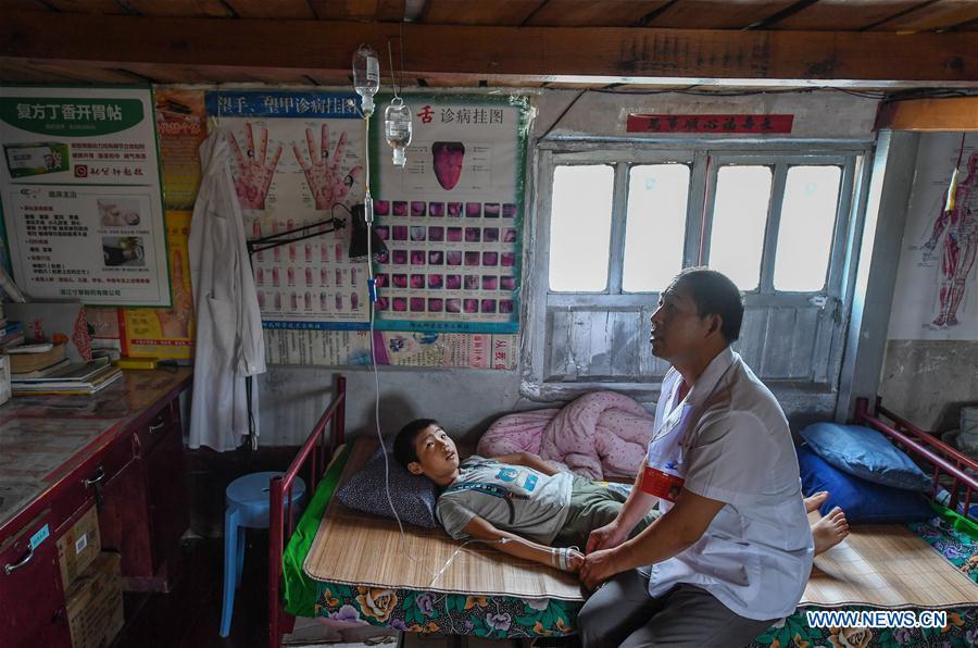 Doctor Li Shaoyou treats a young patient at his boat clinic in Mudundao Village of Bancheng Township, Sihong County, east China\'s Jiangsu Province, June 27, 2018. Li has been offering medical services to fishermen around the Hongze Lake for more than three decades. A large number of medical practitioners are active in China\'s rural areas where health care is still underdeveloped. Under adverse working conditions, they have carried forward the humanitarian spirit and devoted themselves to the health of rural citizens. China will mark its first Medical Workers\' Day on Aug. 19, 2018. (Xinhua/Ji Chunpeng)